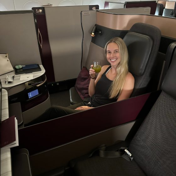 A traveler enjoying a drink in a private Qatar Qsuite on one of Mike's trips
